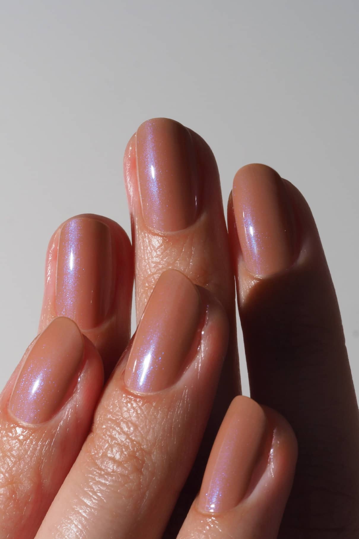 Eine Nahaufnahme einer Hand mit sauber manikürten Nägeln, lackiert in gitti no. 028, einem warmen Mokkabraun-Nude-Ton mit dezentem blauen Schimmer.
