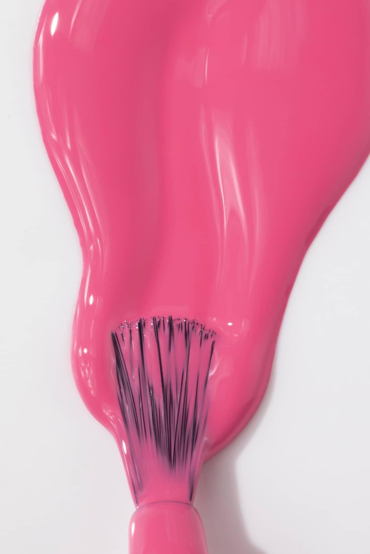 Ein Nagellackpinsel verteilt gitti no. 030, ein leuchtendes Pink, auf eine weiße Fläche.