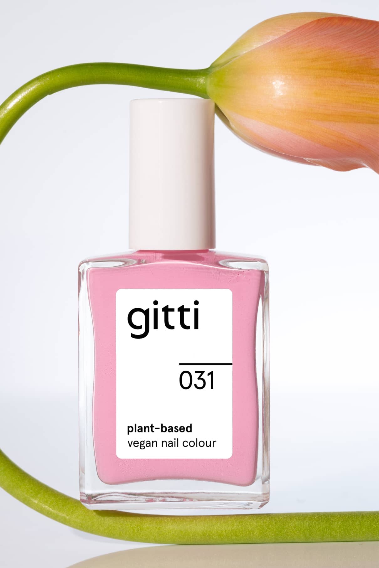Eine Flasche der Nagelfarbe gitti no. 031 Nagelfarbe in Pastellrosa wird mit einem geschwungenen grünen Stiel und einer orange-rosa Blume im Hintergrund präsentiert, was einen subtilen Retro-Look erzeugt.