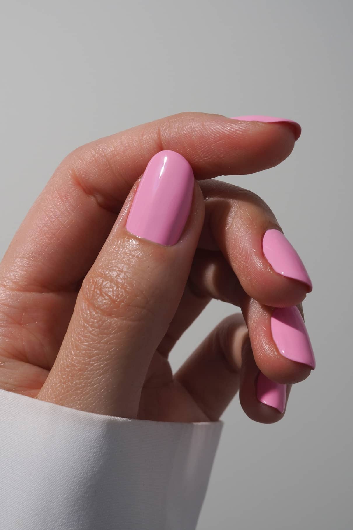Nahaufnahme einer Hand mit sauber manikürten Nägeln, lackiert in glänzendem gitti no. 031 pastellrosa lackiert sind, vor einem neutralen Hintergrund, der dezente Retro-Vibes hervorruft.