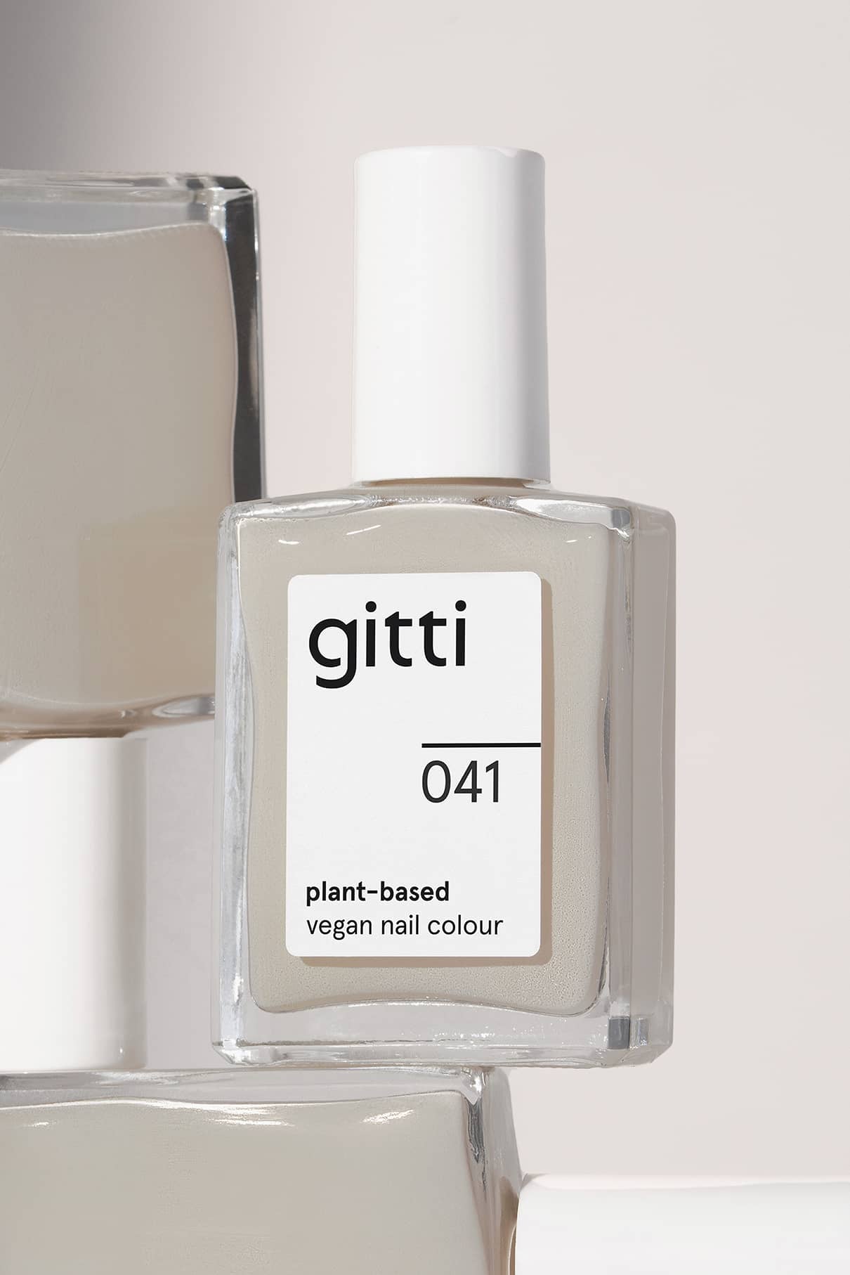 Eine Flasche von gitti no. 041, eine vegane Nagelfarbe auf pflanzlicher Basis in hellem Beige mit sanften Taupe- und Grautönen, wird in einer quadratischen Glasflasche mit weißem Verschluss geliefert.