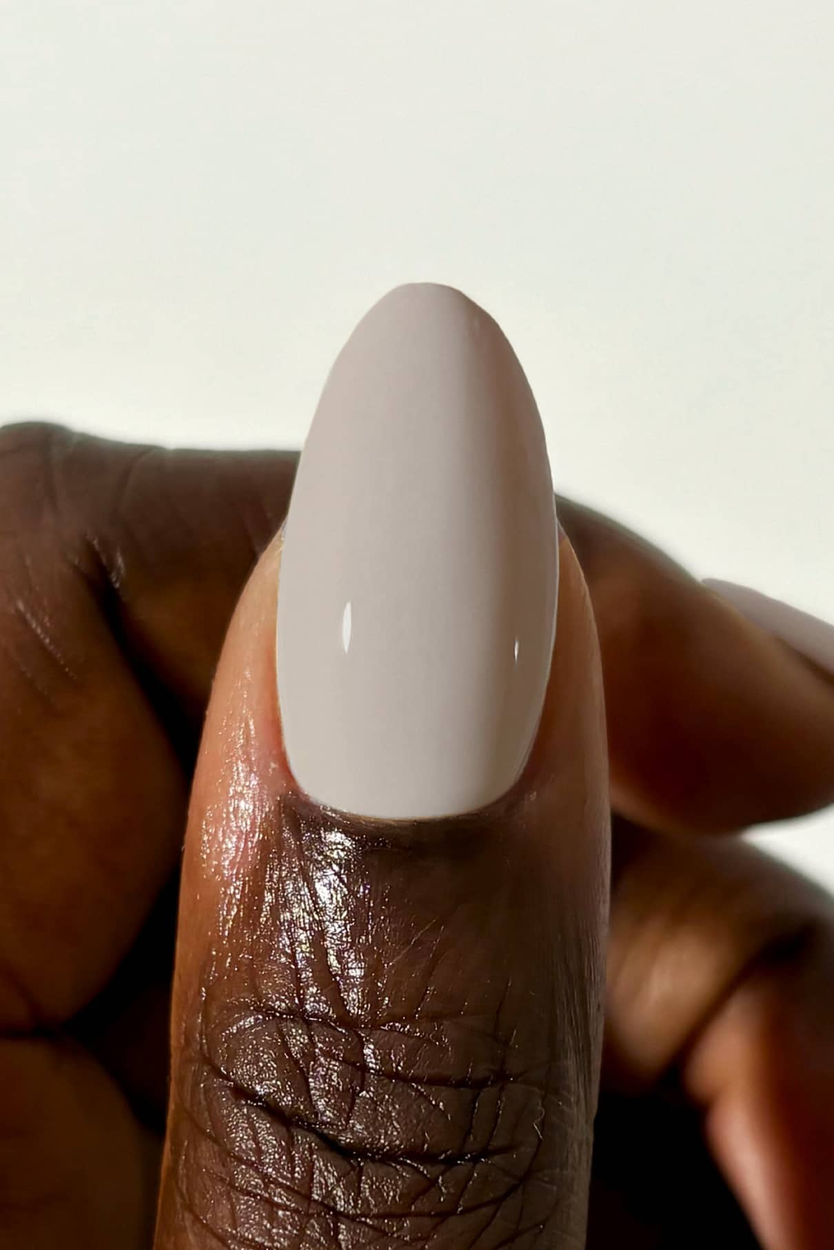 Die Nahaufnahme einer Hand zeigt einen Daumen mit glattem, glänzendem gitti no. 041 Nagellack in sanftem Taupe, der einen subtilen gräulichen Unterton erkennen lässt.