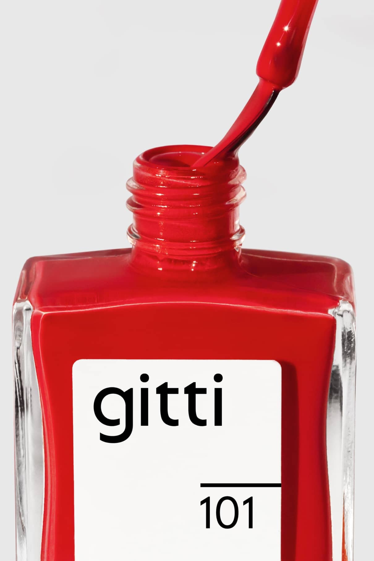 Eine Nahaufnahme einer geöffneten Flasche gitti no. 101 mit rotem Nagellack, wobei der Pinsel herausgezogen wird.