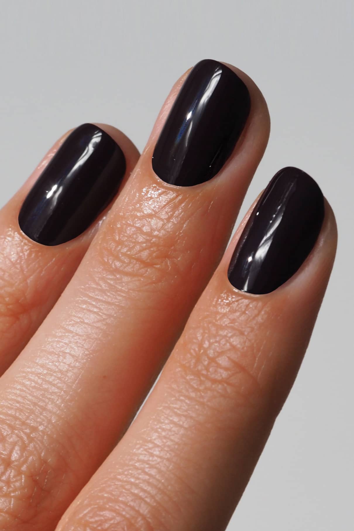 Nahaufnahme von drei Fingern mit kurzen, sauber geformten Nägeln, die mit gitti Nr. 103 in einem glänzenden, intensiven Aubergine-Ton lackiert wurden. 103.