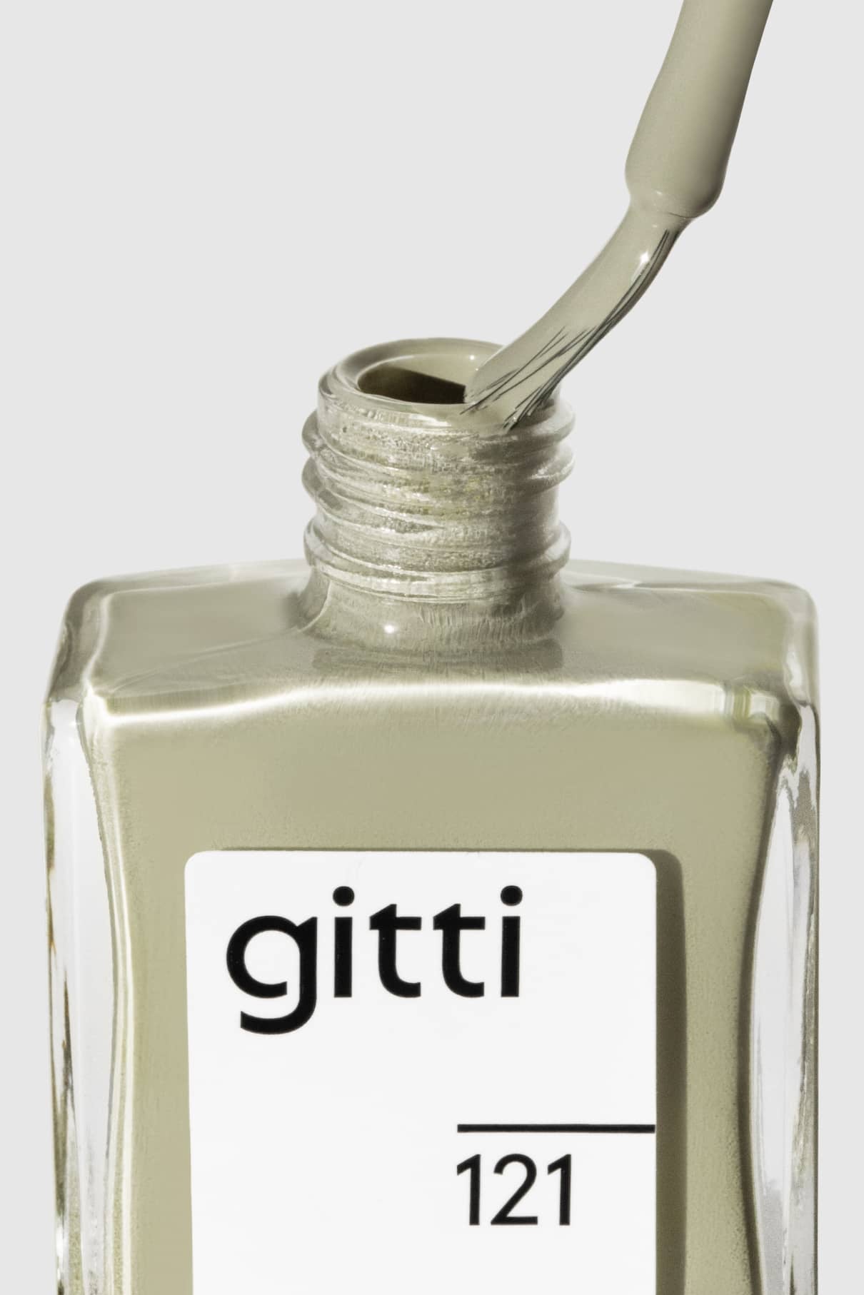 Eine Nahaufnahme einer geöffneten Flasche gitti no. 121 Nagellack, wobei der Pinsel entfernt und mit einem zarten Grün überzogen wird, das an Salbei-Wandfarbe erinnert.