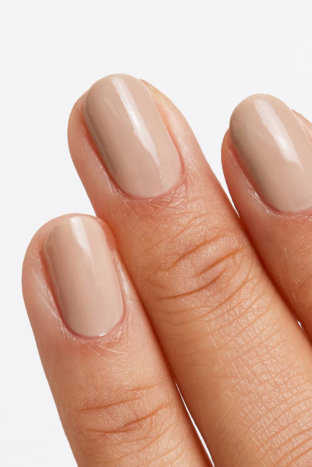 Eine Nahaufnahme von drei Fingern mit kurzen, ordentlich manikürten Nägeln, die mit gitti Nr. 124 in einem glänzenden, subtilen sandbeigen Nude-Ton lackiert wurden. 124.