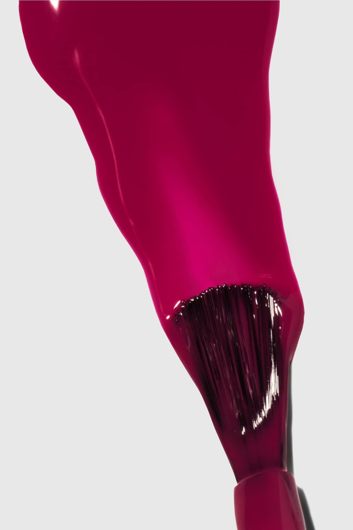 Eine Nahaufnahme eines Gitti Nr. 125 Nagellackpinsel, bedeckt mit glänzendem bierig-violettem Magentarot vor einem schlichten hellen Hintergrund.