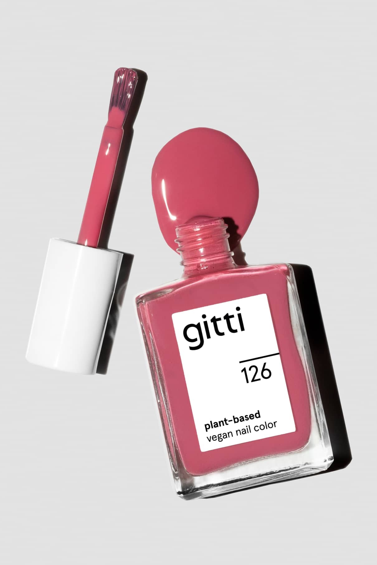 Eine Flasche gitti no. 126 pflanzliche vegane Nagelfarbe in sanftes Rot, ohne Deckel und mit daneben liegendem Pinsel, zeigt Pastellrot auf dem Pinsel und um die Flaschenöffnung.