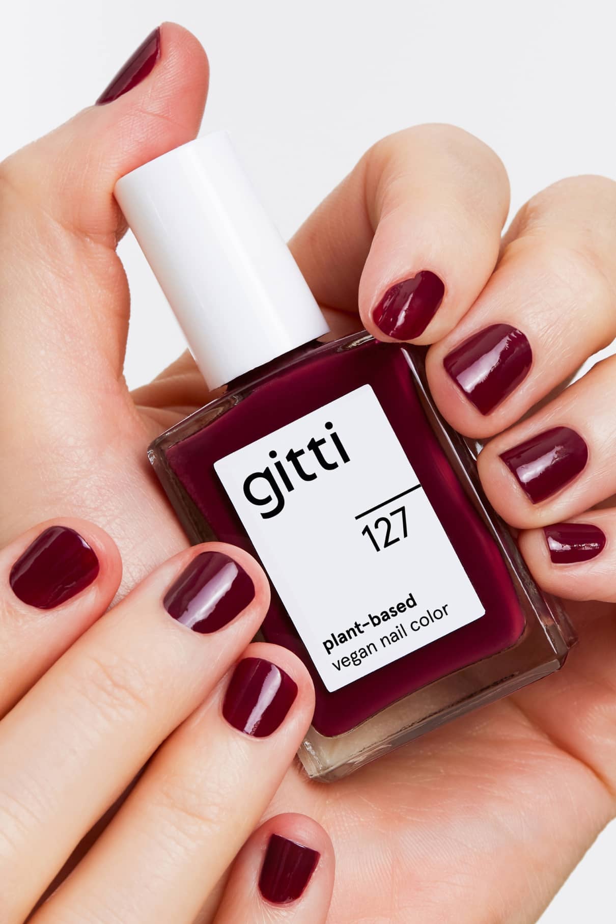 Eine Hand hält eine Flasche gitti no. 127; die Nägel sind in demselben beerigen Pflaumenton lackiert, der an einen tiefroten Lippenstift erinnert.