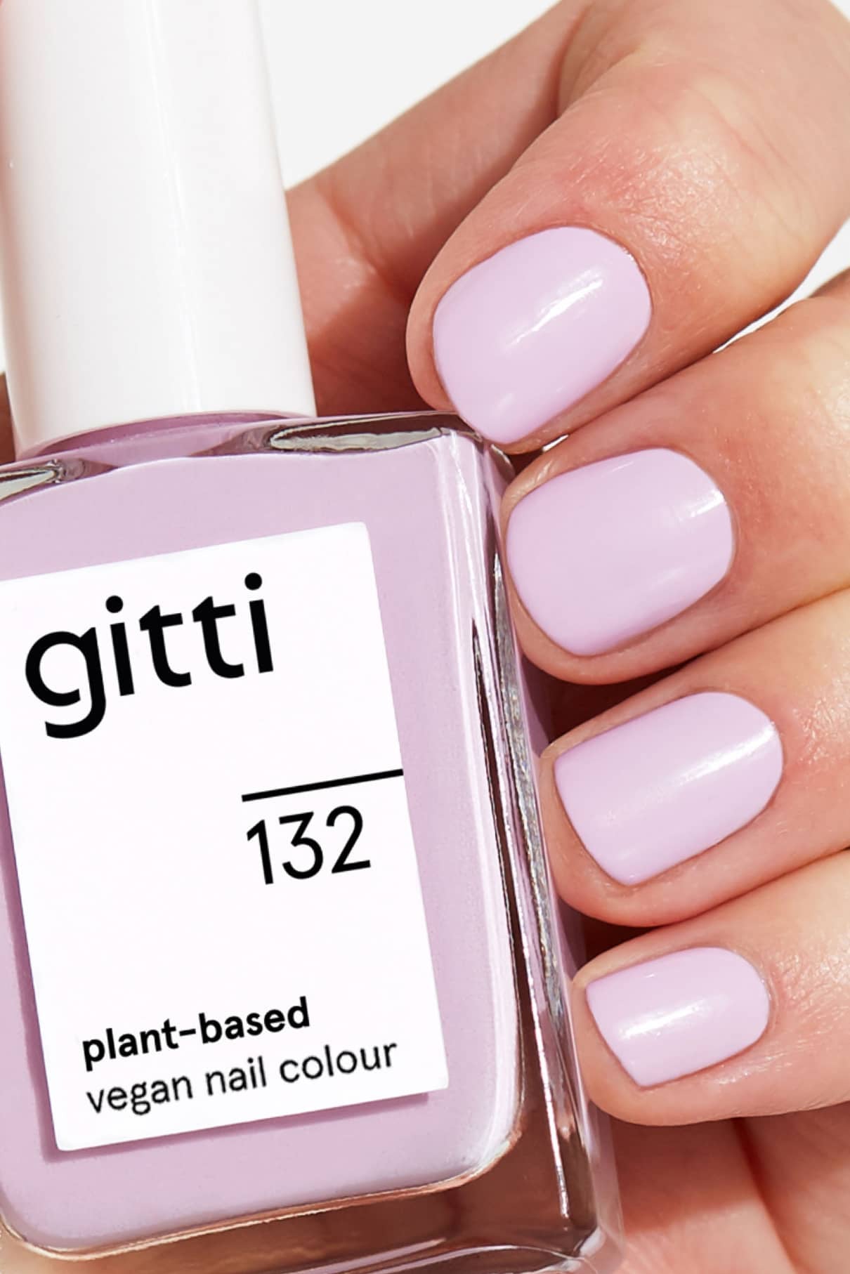Eine Hand mit sauber manikürten, in Pastelllila lackierten Nägeln hält eine Flasche gitti no. 132 pflanzlicher, veganer Nagellack.