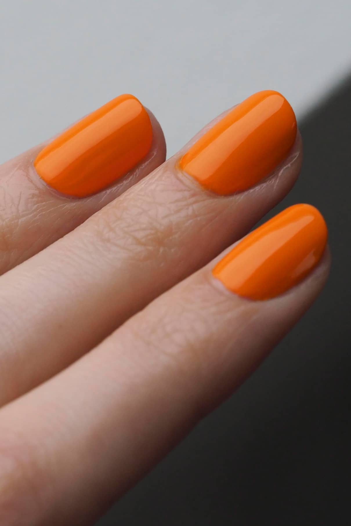 Nahaufnahme von drei Fingern mit sauber manikürten Nägeln, die in gitti no. 133, einem leuchtenden Orangeton.