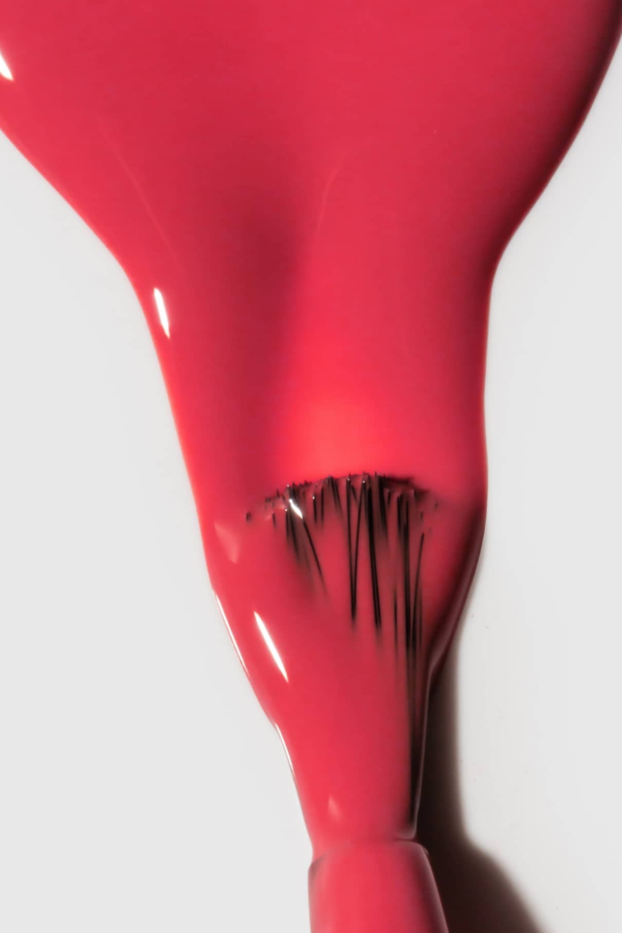 Eine Nahaufnahme eines Nagellackpinsels, der Gitti Nr. 131, ein frischer hellroter Farbton, auf einer weißen Fläche.