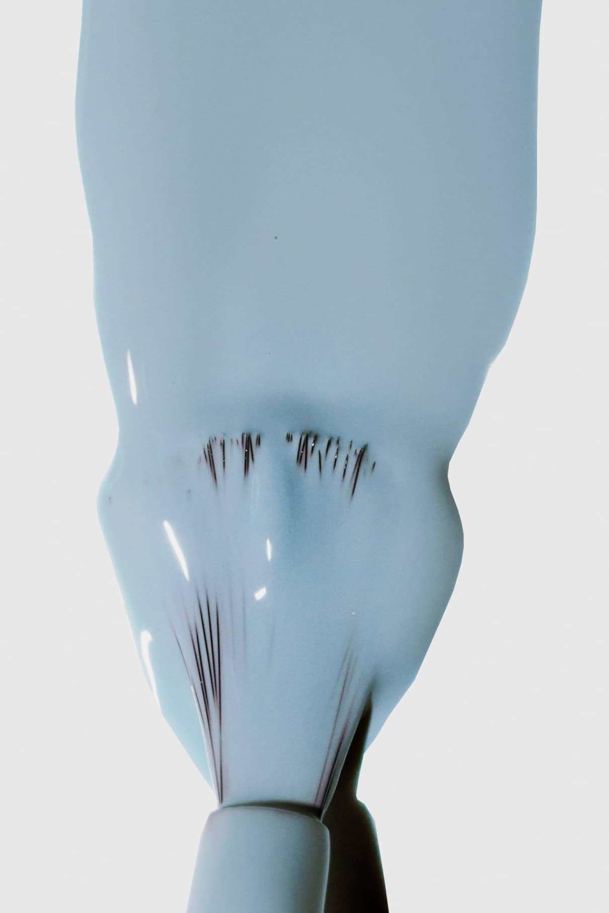 Ein Pinsel gleitet mit gitti no. 138, ein kühler Blauton, über eine weiße Fläche und hinterlässt sichtbare Borstenspuren in der nassen Farbe.