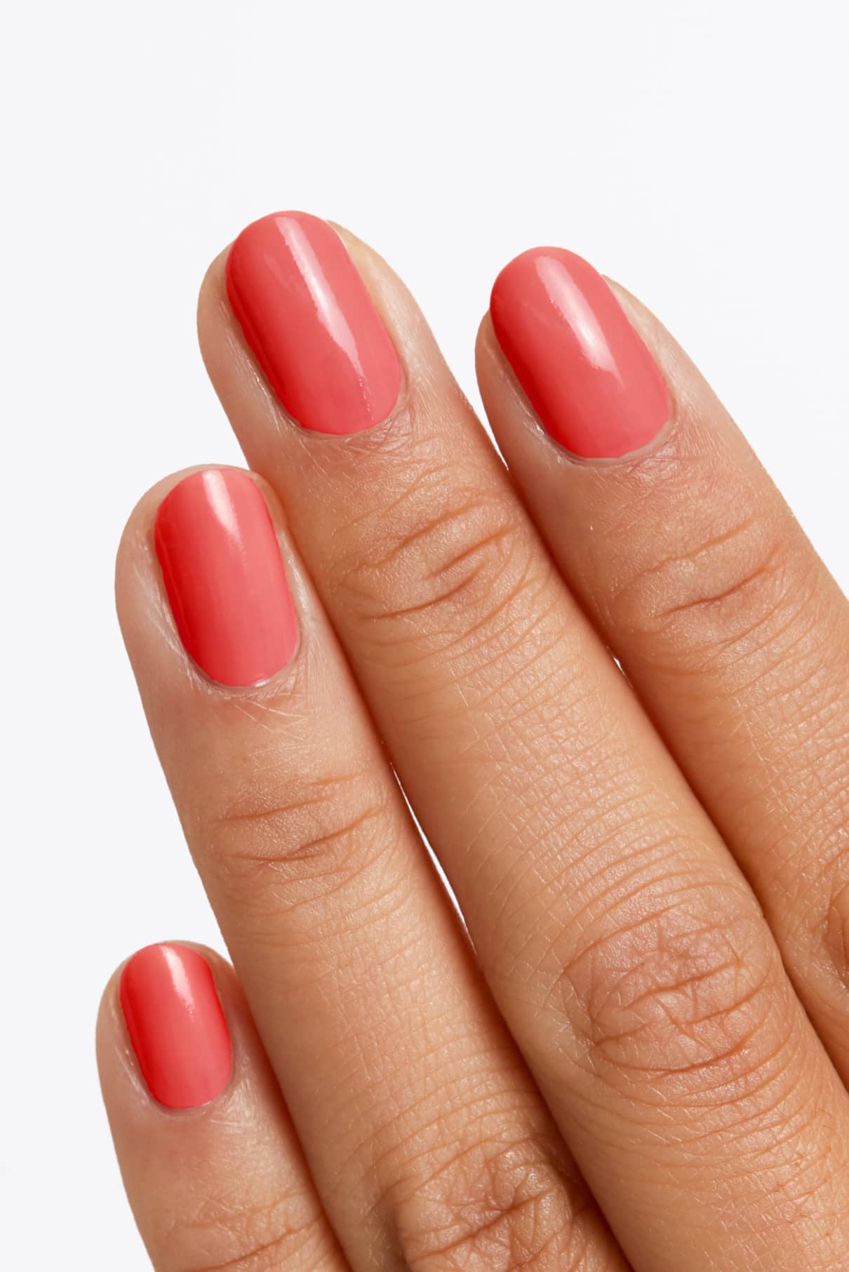 Eine Hand mit sauber manikürten Nägeln, lackiert in gitti no. 140, einem glänzenden hellen Korall-Farbton mit rosigem Unterton, vor einem schlichten weißen Hintergrund.