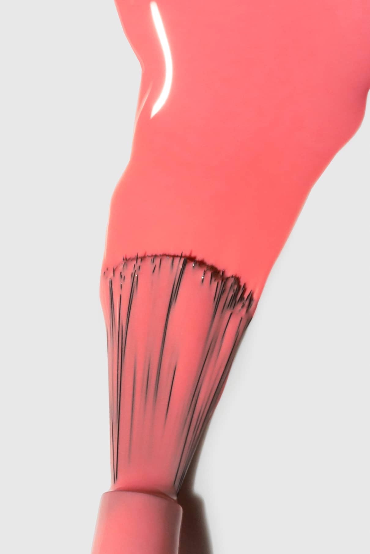 Nahaufnahme eines gitti no. 140 Nagellackpinsel in einem hellen Korallenrosa mit rosigem Unterton, der sich sanft auf einer weißen Fläche verteilt.