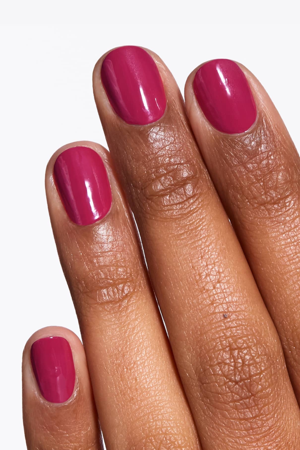 Eine Hand mit kurzen, sauber manikürten Nägeln, lackiert in dem glänzenden, leuchtendes Rosa von gitti no. 143.