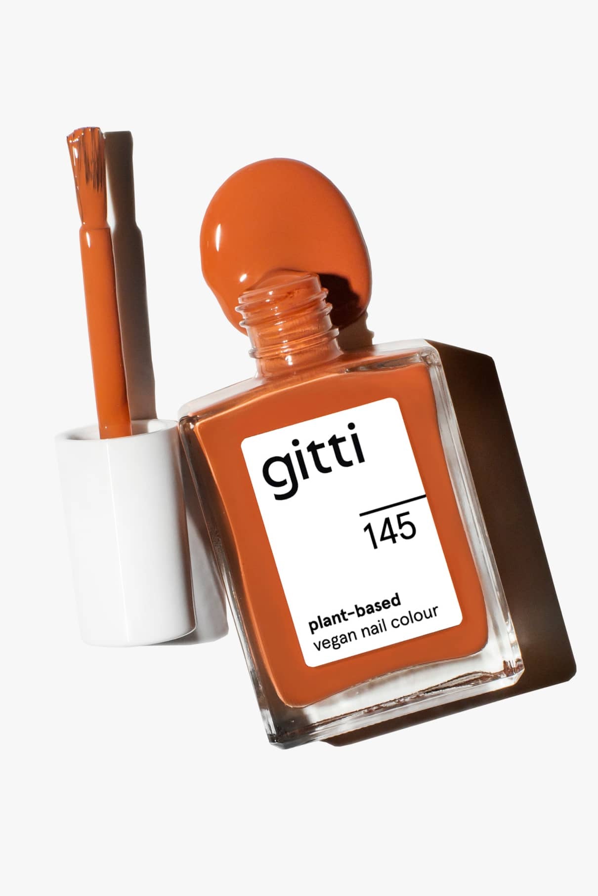 Eine Flasche orange-brauner veganer Nagellack, gitti no. 145 in Zimtbraun, mit dem Pinselapplikator daneben.