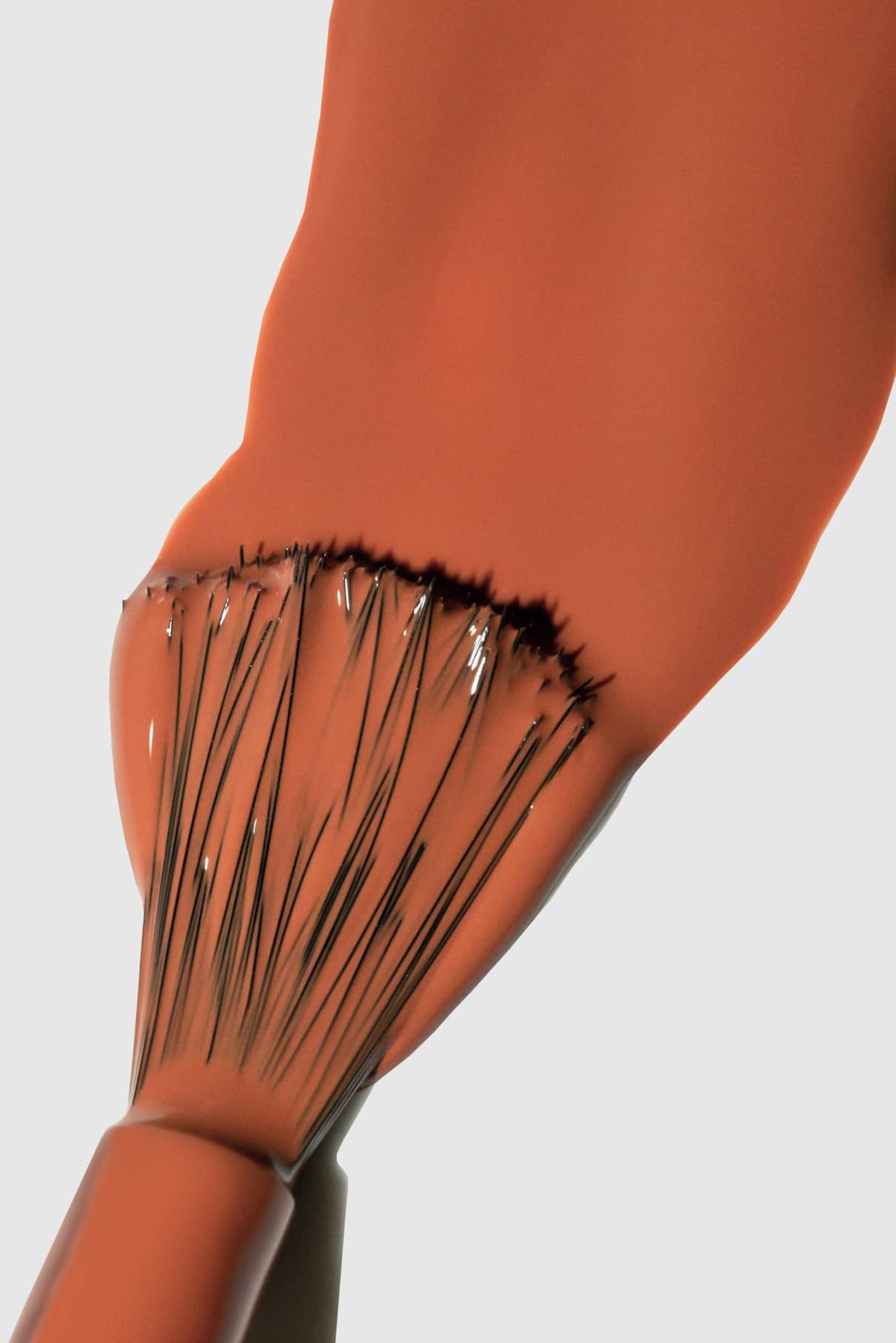Nahaufnahme eines Pinsels, der eine dicke Schicht von Gitti Nr. 145, einer orangefarbenen und warm-braunen Farbe, auf einer glatten Oberfläche.