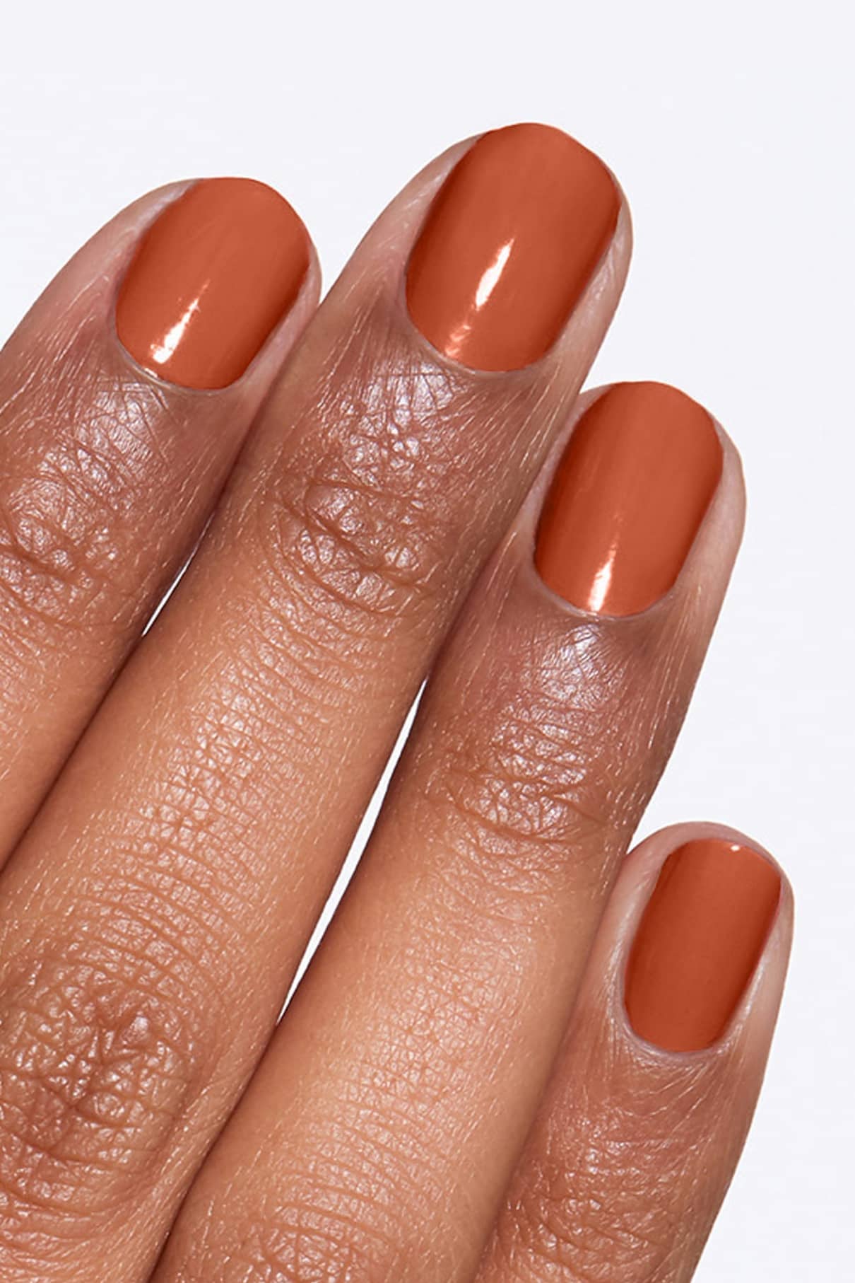 Eine Hand mit kurzen, sauber manikürten Nägeln, lackiert in glänzendem Gitti Nr. 145, mit einem warmen braunen Nagellack.