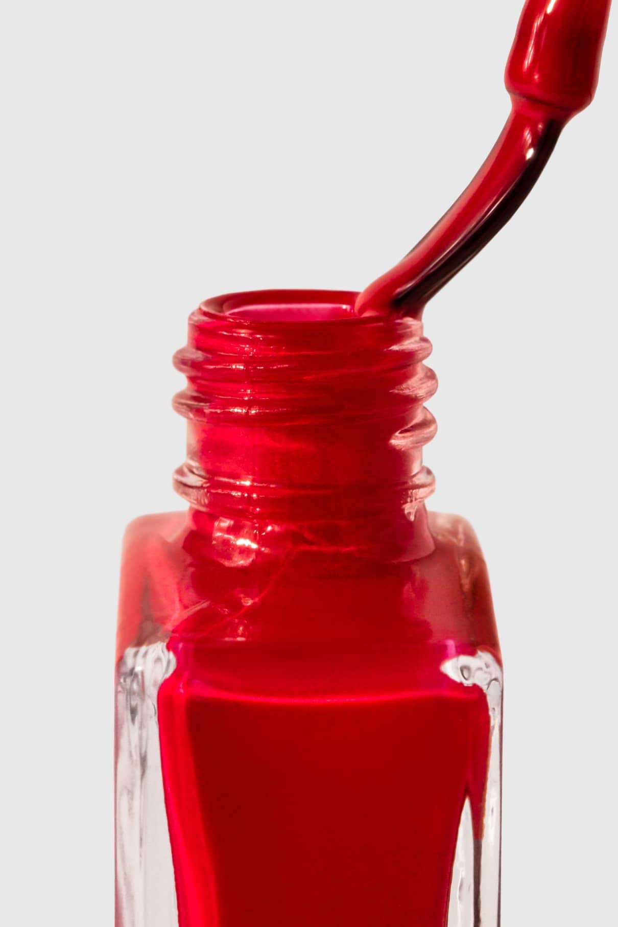 Nahaufnahme einer gitti no. 147 Nagellackflasche in klassischem Rot, mit eingetauchtem Pinsel, vor einem schlichten hellen Hintergrund.