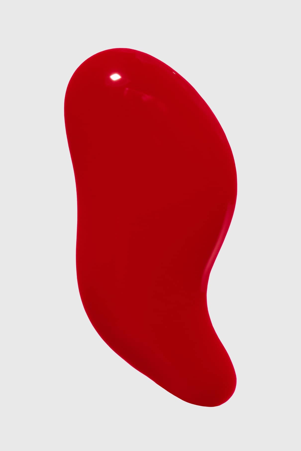 Ein roter, unregelmäßig geformter Flüssigkeitsfleck aus Gitti Nr. 147 hebt sich von einem schlichten hellgrauen Hintergrund ab.
