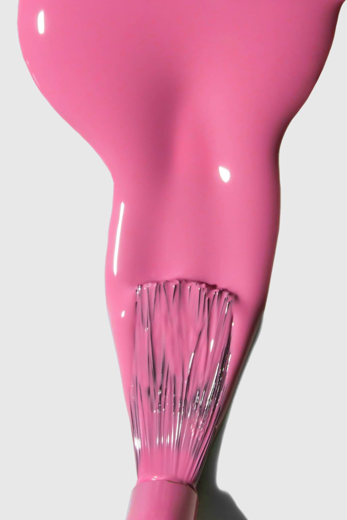 Ein Pinsel trägt eine dicke Schicht von gitti no. 154, einem glänzenden, warmrosa Nagellack, auf eine weiße Fläche auf.
