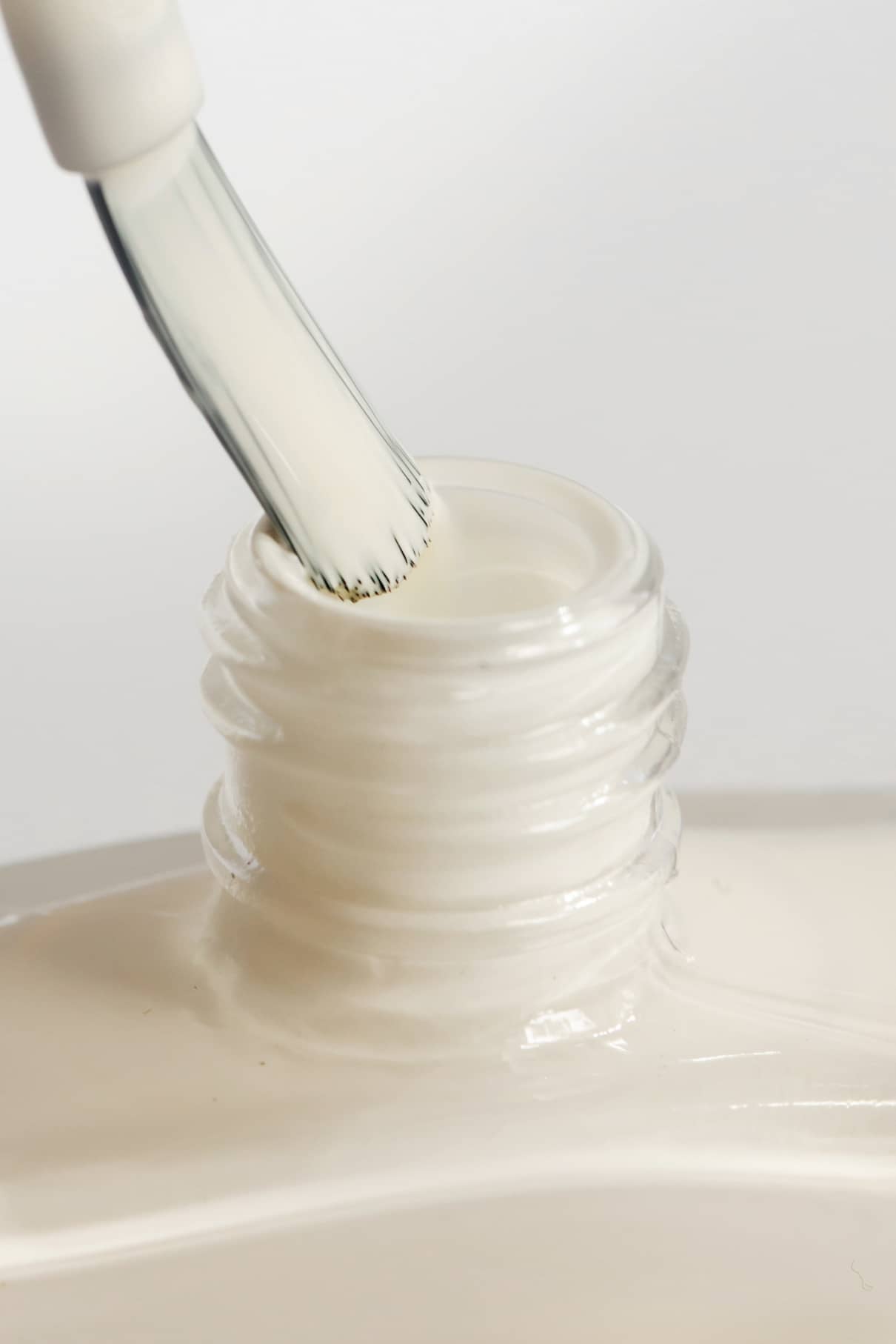 Nahaufnahme eines Pinsels, der in eine Flasche mit gitti no. 157, einem cremeweißen Nagellack mit einem cremefarbenen Finish.