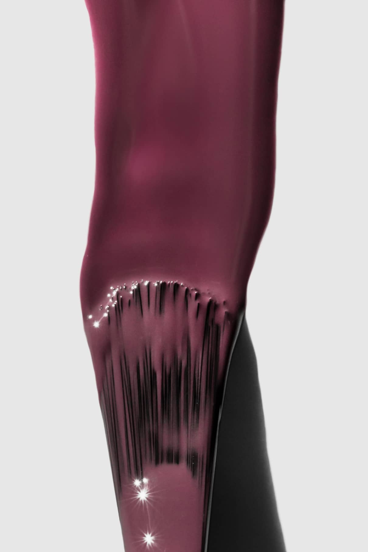 Nahaufnahme eines Pinsels, mit dem gitti no. 164, ein glänzender dunkelrosa Nagellack mit rötlichem Lila und blauen Untertönen, auf einen Nagel auf, während das Licht von der nassen Oberfläche reflektiert wird.