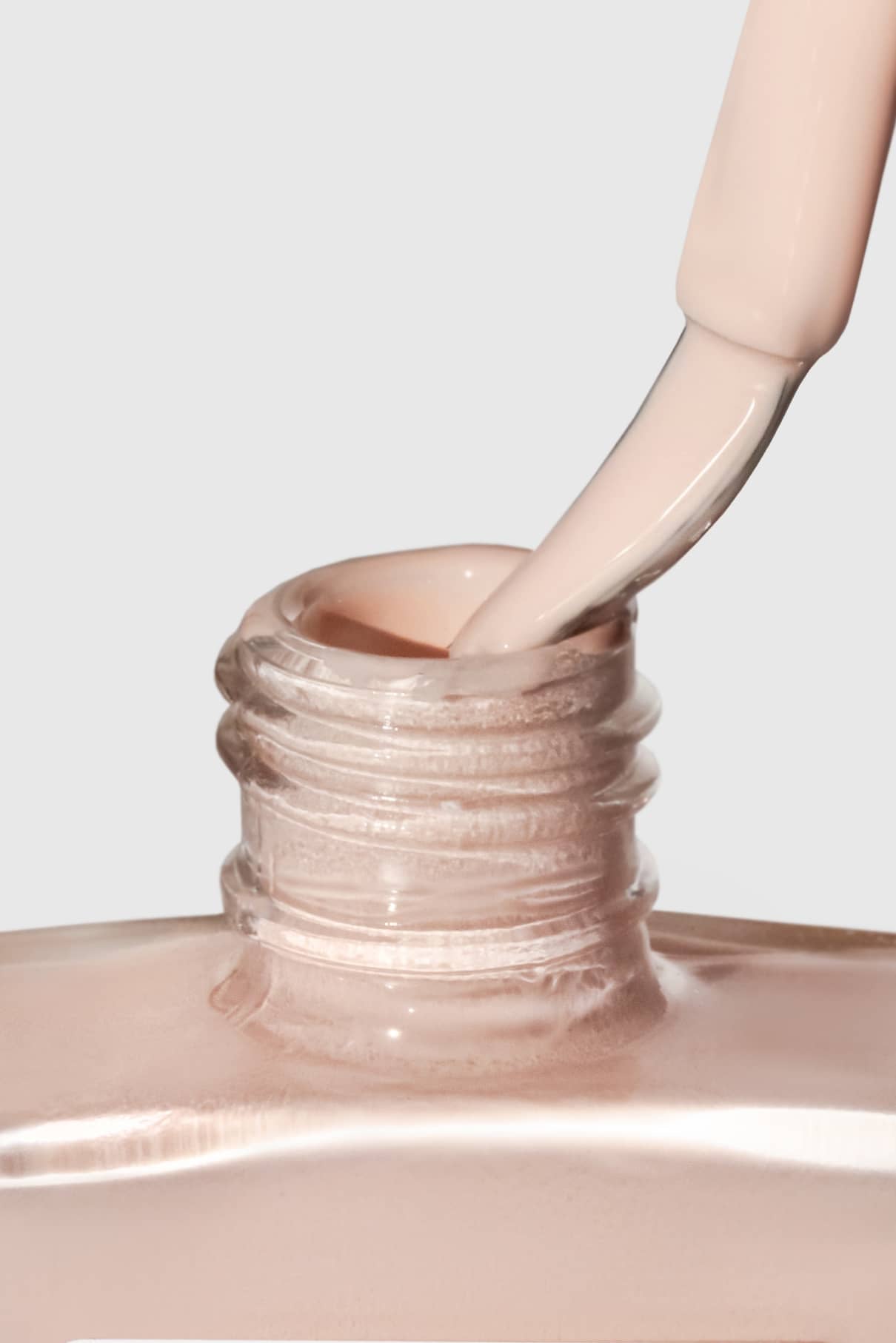 Nahaufnahme eines Pinsels, der in eine Flasche mit Gitti Nr. 169, einem hellbeigen Nagellack, vor einem neutralen Hintergrund.