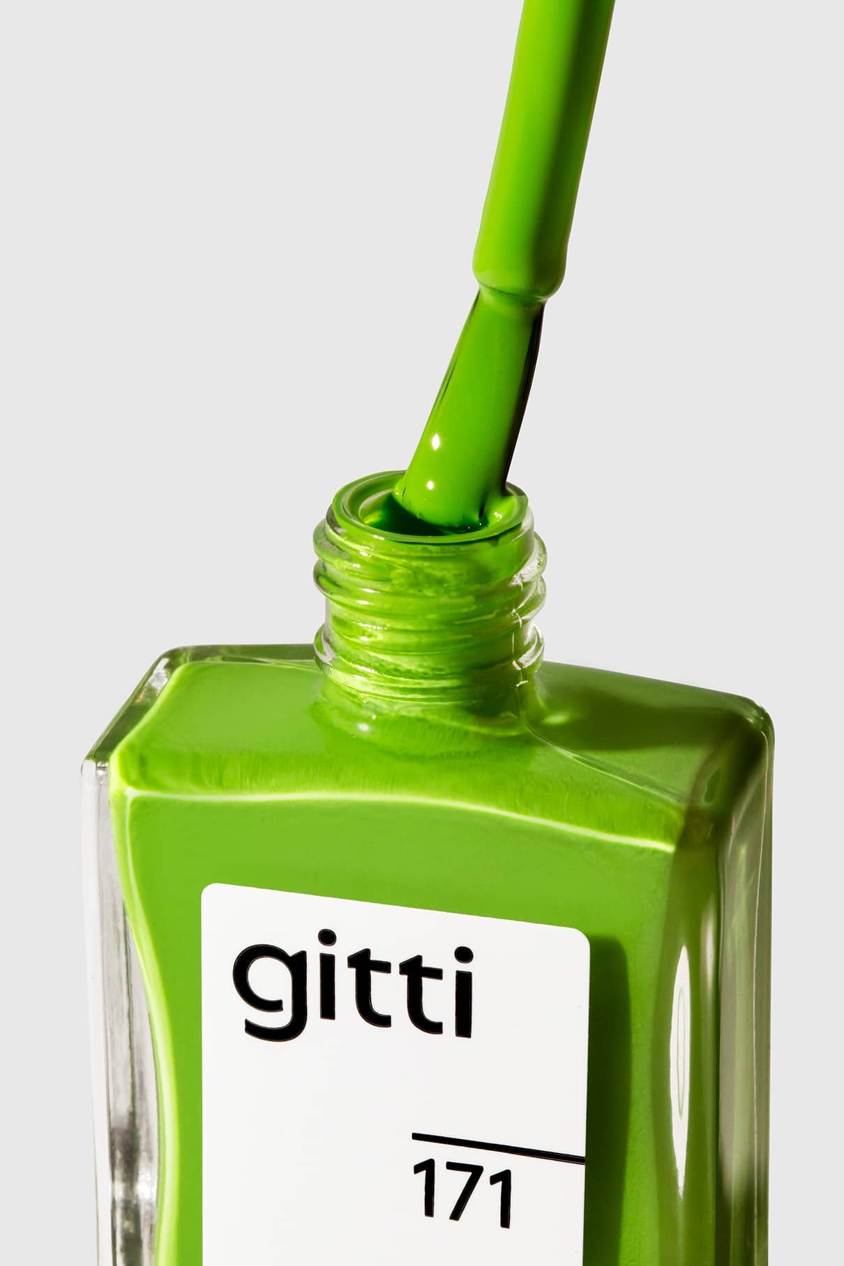 Eine Nahaufnahme einer grünen Nagellackflasche mit der Aufschrift gitti no. 171, wobei der mit frischem Grasgrün bestrichene Pinsel aus der Flasche gezogen wird.