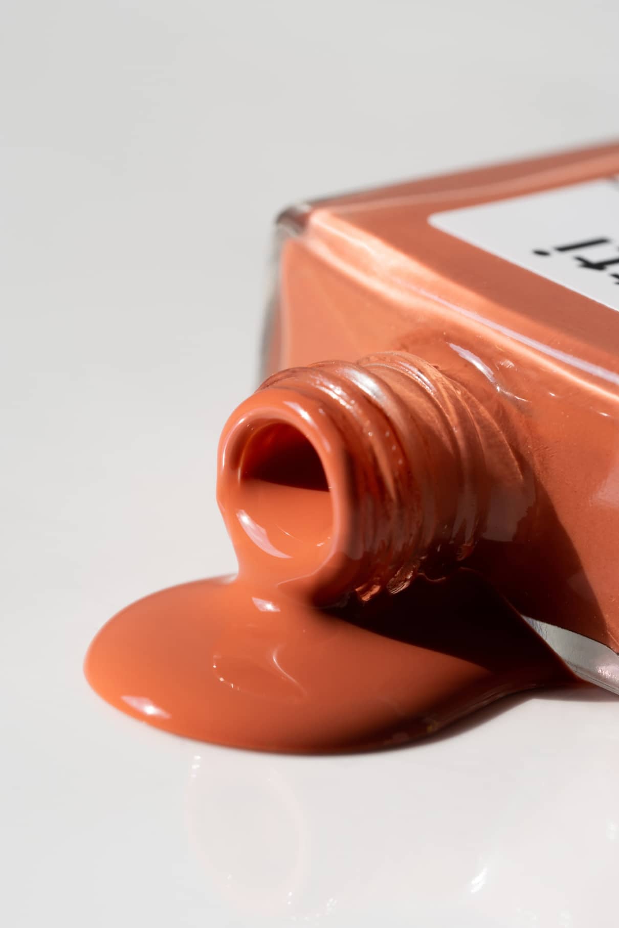 Eine Flasche mit Gitti Nr. 172, ein pfirsichfarbener Nagellack mit warmen Untertönen, kippte um und verschüttete seinen sanften Farbton auf eine weiße Fläche.