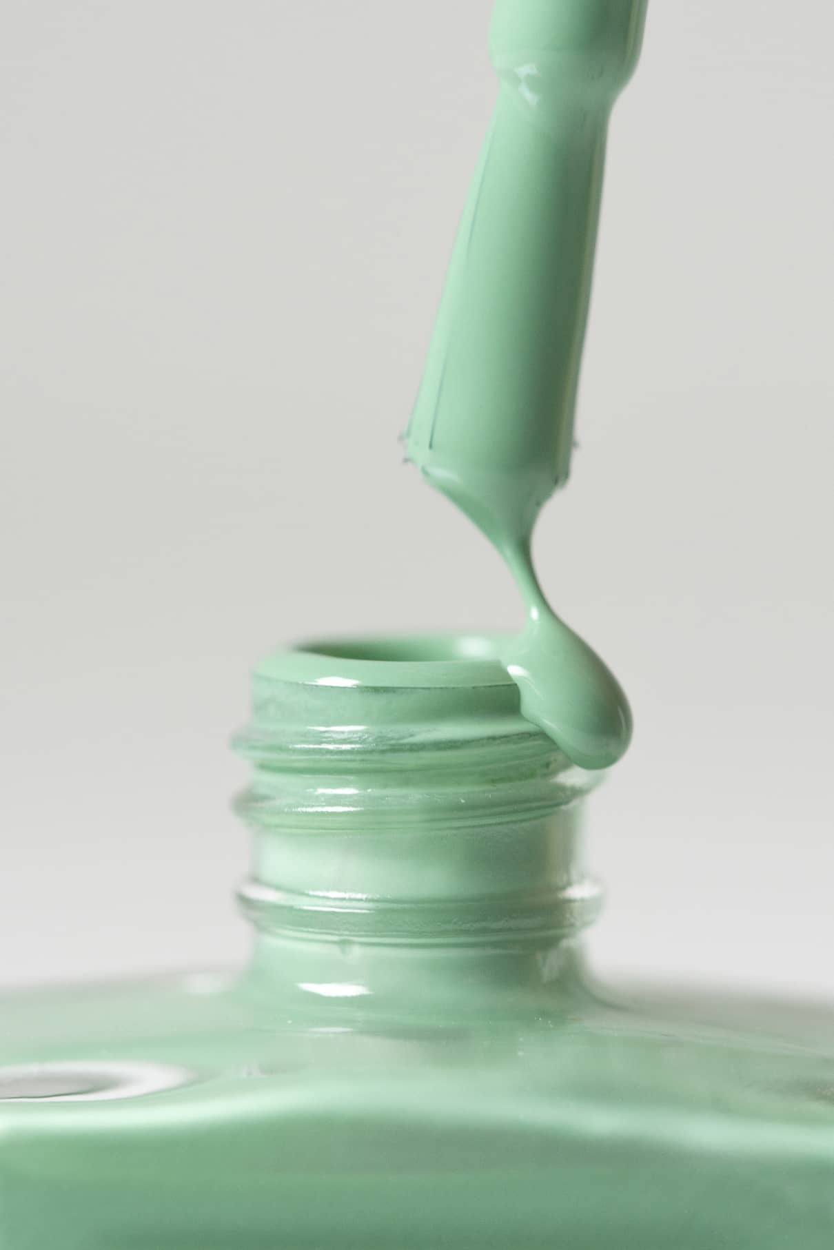 Nahaufnahme eines Nagellackpinsels mit Gitti Nr. 177, einem sanften Grünton, der aus einer offenen Flasche vor einem schlichten Hintergrund gezogen wird.