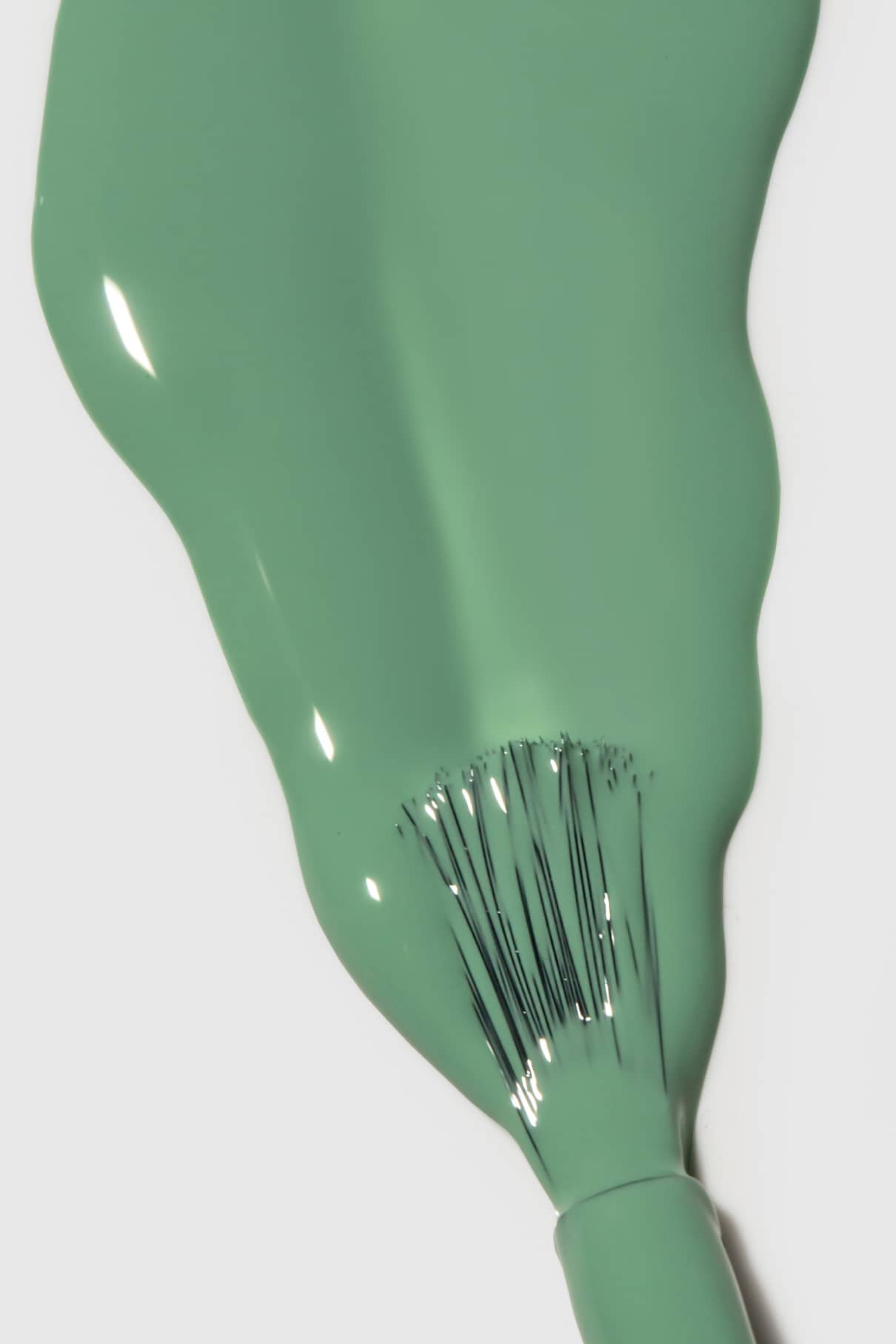 Nahaufnahme eines Nagellackpinsels, mit dem glänzender gitti no. 177 jade Grünton Nagellack auf eine weiße Fläche auf.