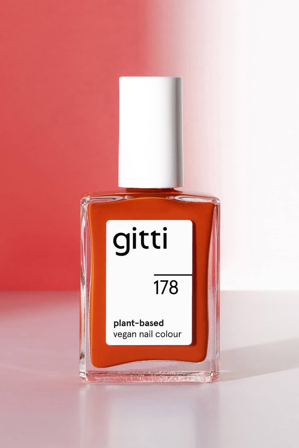 Eine Flasche gitti no. 178 pflanzliche vegane Nagelfarbe, ein warmer orangeroter Farbton mit weißer Kappe, dargestellt vor einem sanft schattierten Hintergrund.