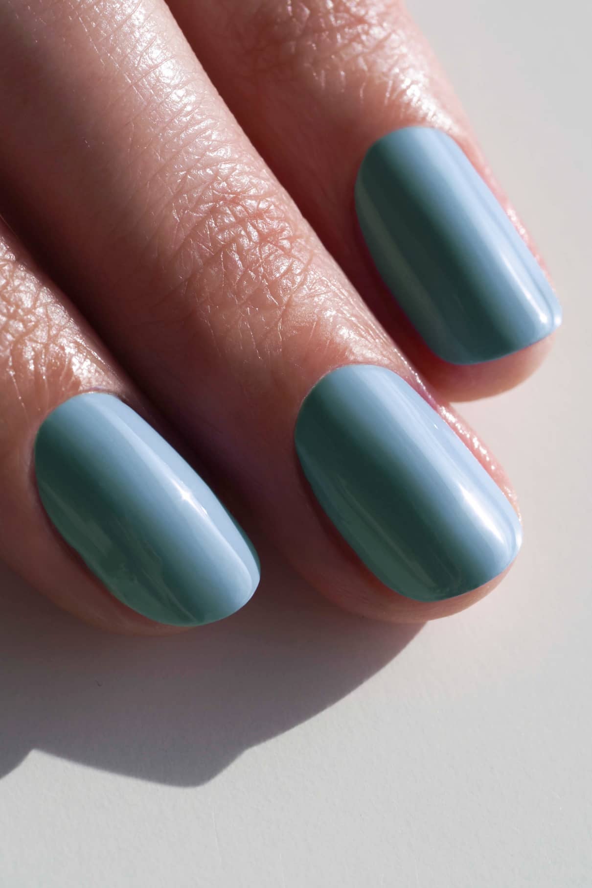 Nahaufnahme von drei Fingern mit glatten, glänzenden Nägeln, die in gitti no. 189, einem gedeckten Blauton, unter natürlichem Licht.