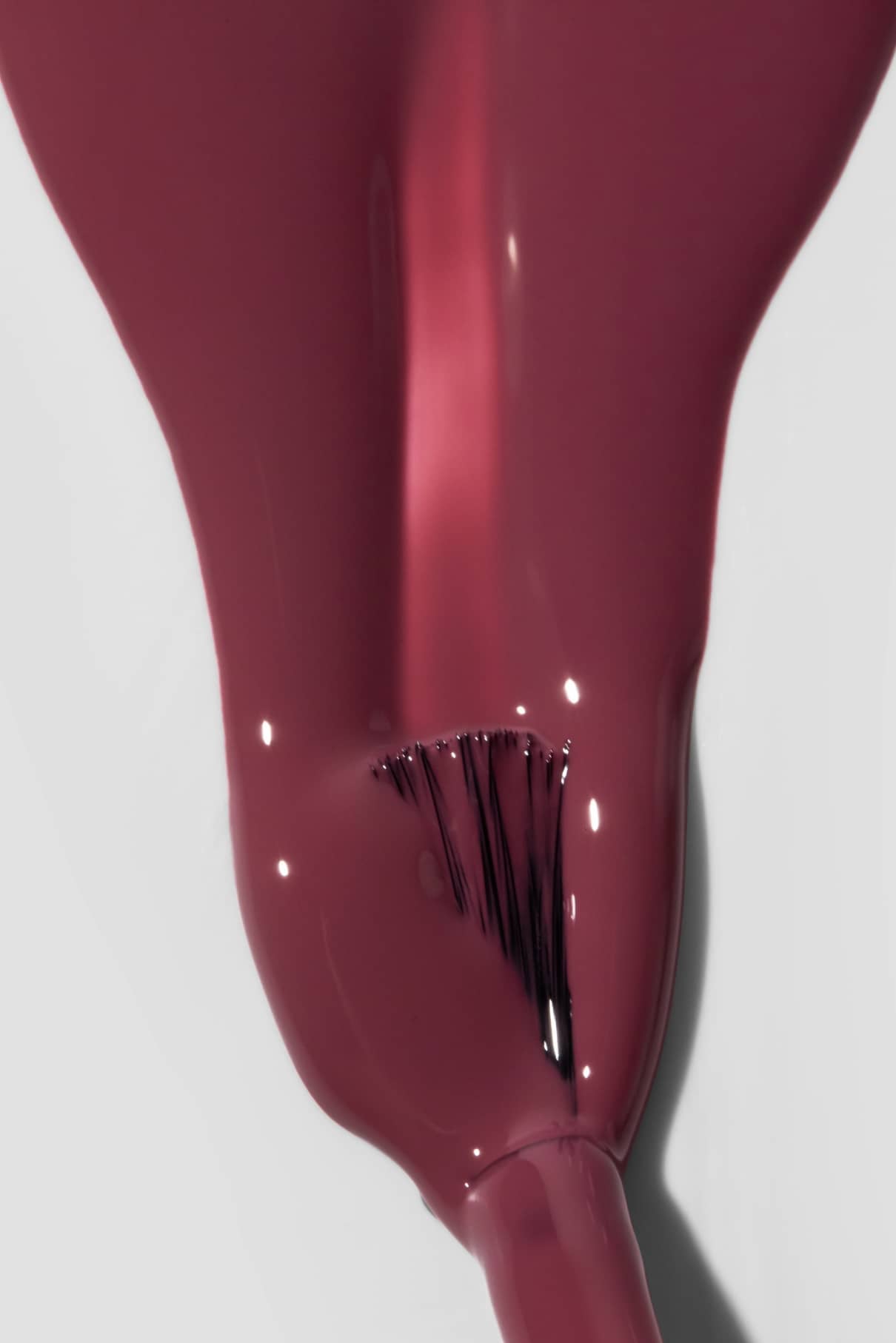 Nahaufnahme eines Nagellackpinsels, mit dem glänzender gitti no. 191 Beerenrosa Nagellack auf eine glatte Oberfläche auf.