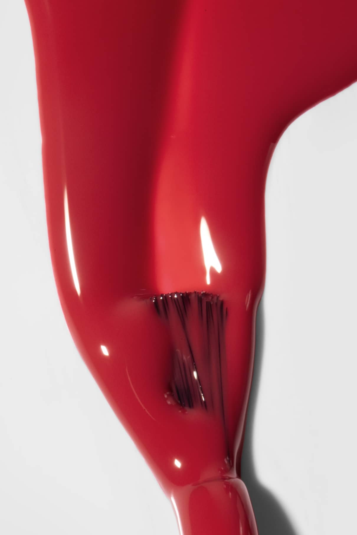 Eine Nahaufnahme von gitti no. 192 Nagellack in leuchtendes Rot, der mit einem Pinsel auf eine weiße Fläche aufgetragen wird und dabei seine glänzende Textur und seinen Nassglanz zeigt.