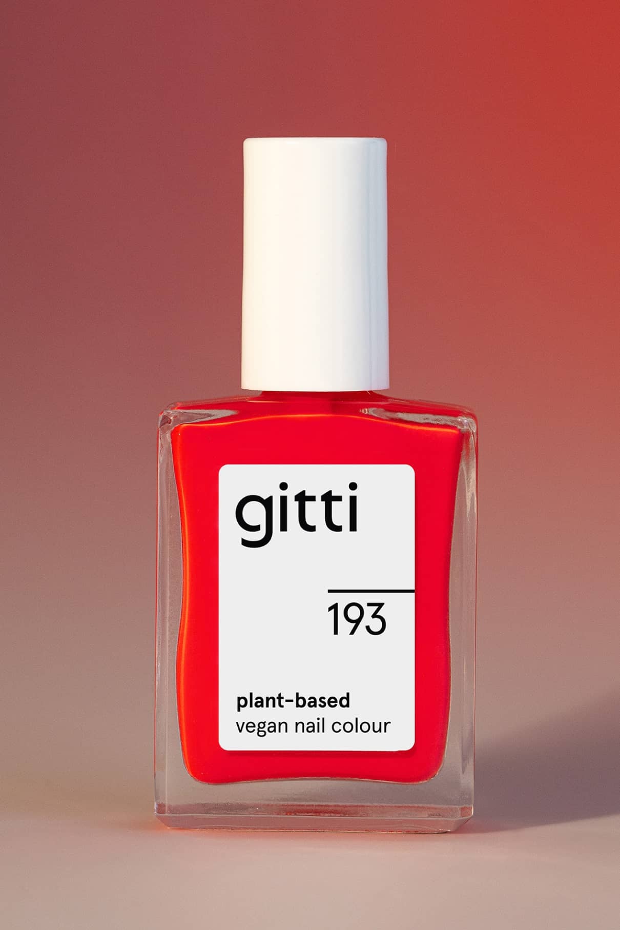 Eine Flasche gitti no. 193 pflanzliche vegane Nagelfarbe mit weißer Kappe und kräftigem Rot-Lack ist vor einem roten Hintergrund mit Farbverlauf abgebildet.