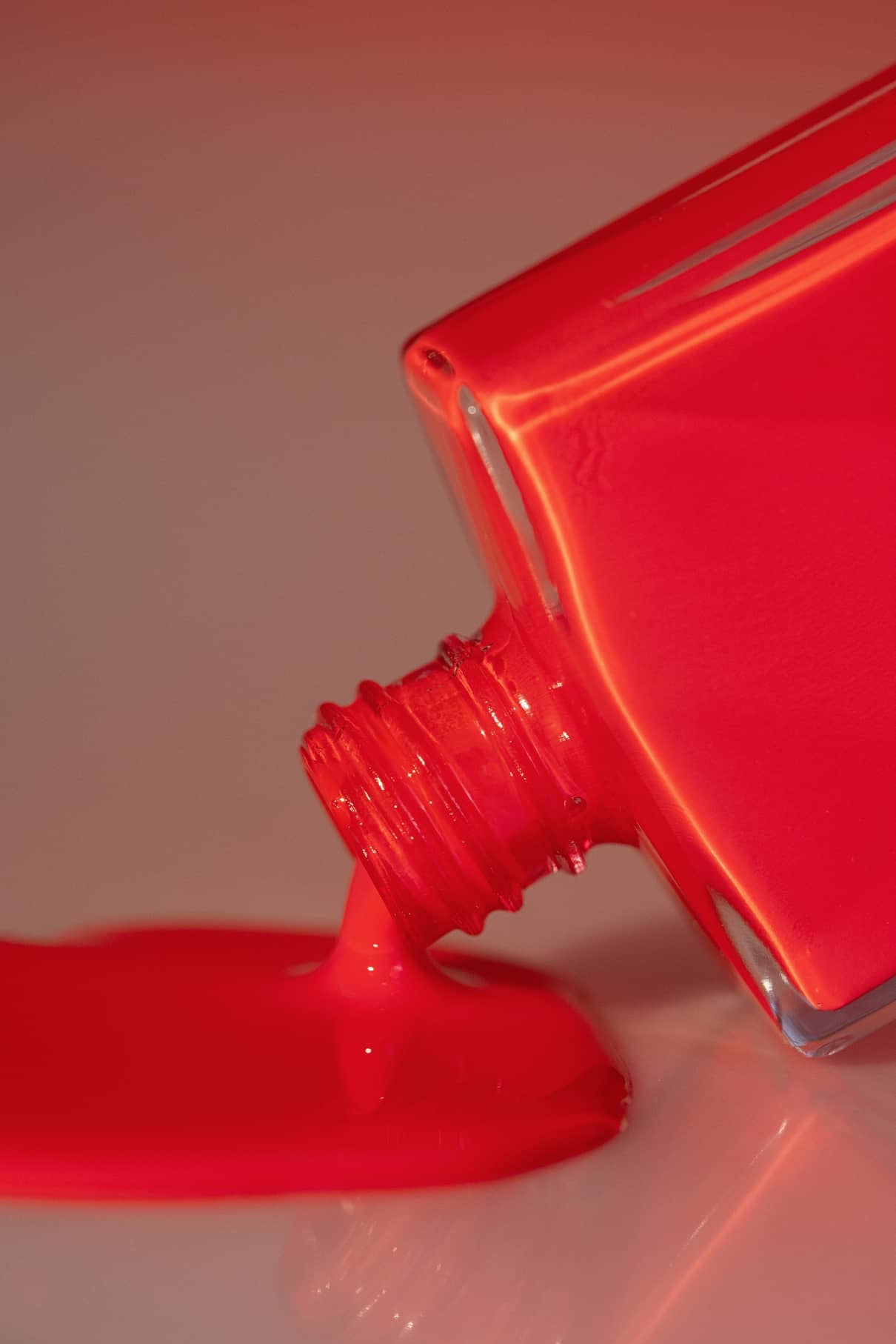 Eine Flasche gitti no. 193 Nagellack in kräftigem Rot kippt um und ergießt sich auf eine glatte, helle Fläche.