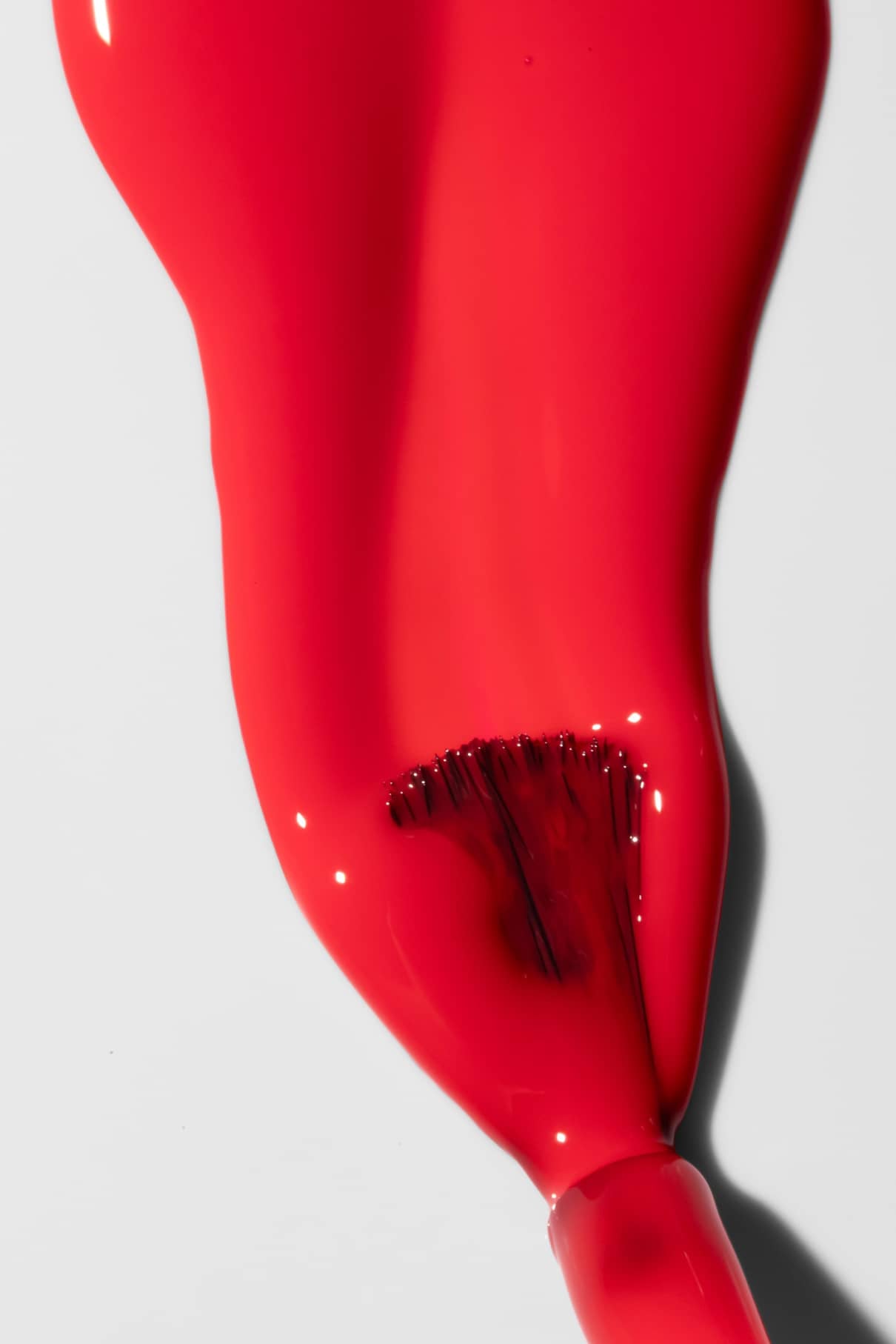 Nahaufnahme eines Nagellackpinsels, mit dem Gitti Nr. 193 - ein leuchtend roter Farbton - auf eine glatte weiße Oberfläche aufträgt.