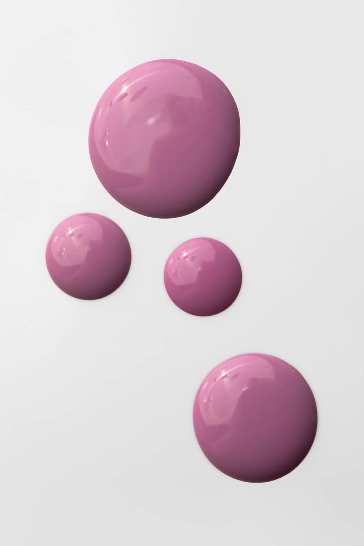 Vier runde Pfützen aus glänzender rosa Flüssigkeit mit blauem Unterton, die mit gitti Nr. 194 erstellt wurden, sind auf einem weißen Hintergrund angeordnet und variieren in ihrer Größe.