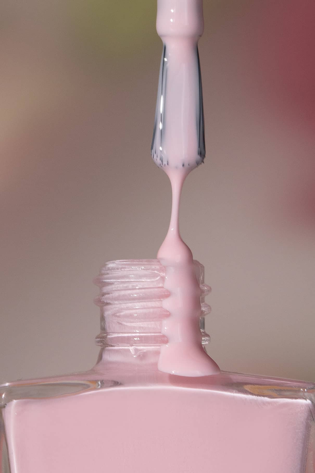 Nahaufnahme eines Pinsels mit gitti no. 198 Nagellack in Hellrosa, der aus einer Glasflasche gezogen wird, während der kühle, zarte Lack zurück in den Behälter tropft.