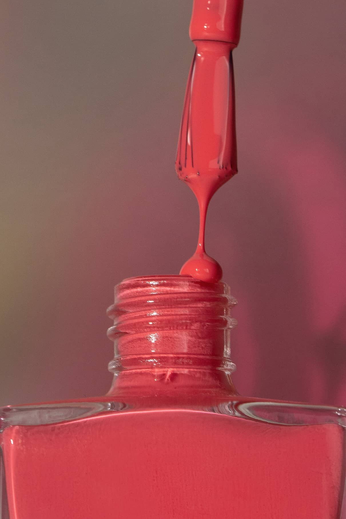 Ein in gitti no. getauchter Pinsel 199 getaucht ist, schwebt über der offenen Flasche, aus der ein Tropfen des leuchtenden Lacks fallen wird.