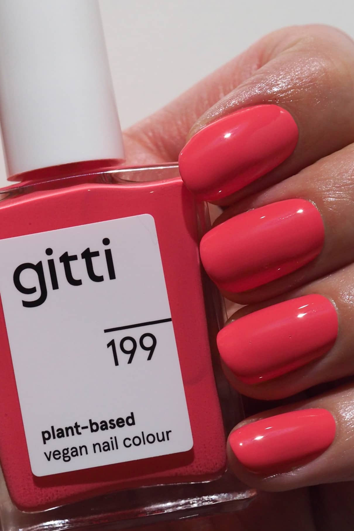 Eine Hand hält eine Flasche gitti no. 199 Nagellack in einem leuchtenden Rosa-Ton, perfekt für gewagte oder subtile Farbmischungen.