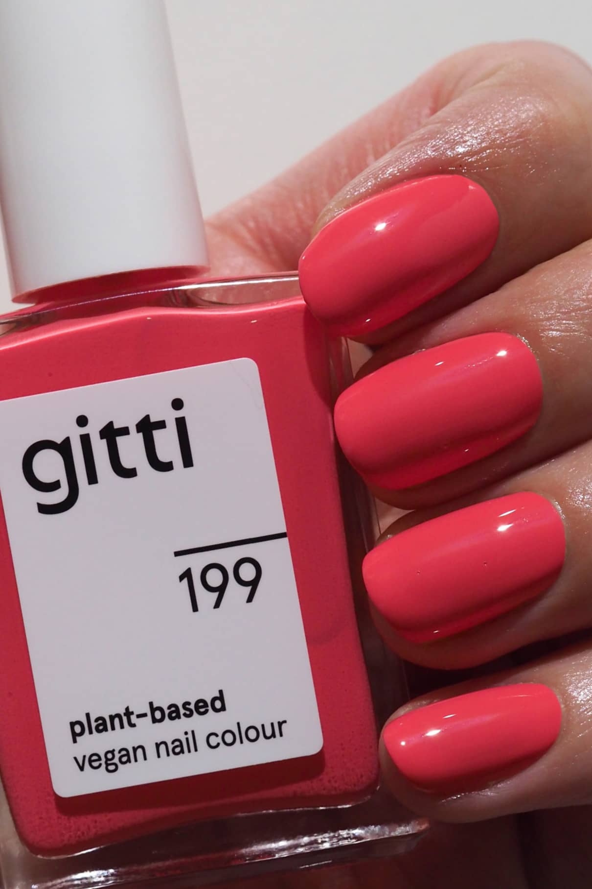 Eine Hand hält eine Flasche gitti no. 199 Nagellack in einem leuchtenden Rosa-Ton, perfekt für gewagte oder subtile Farbmischungen.