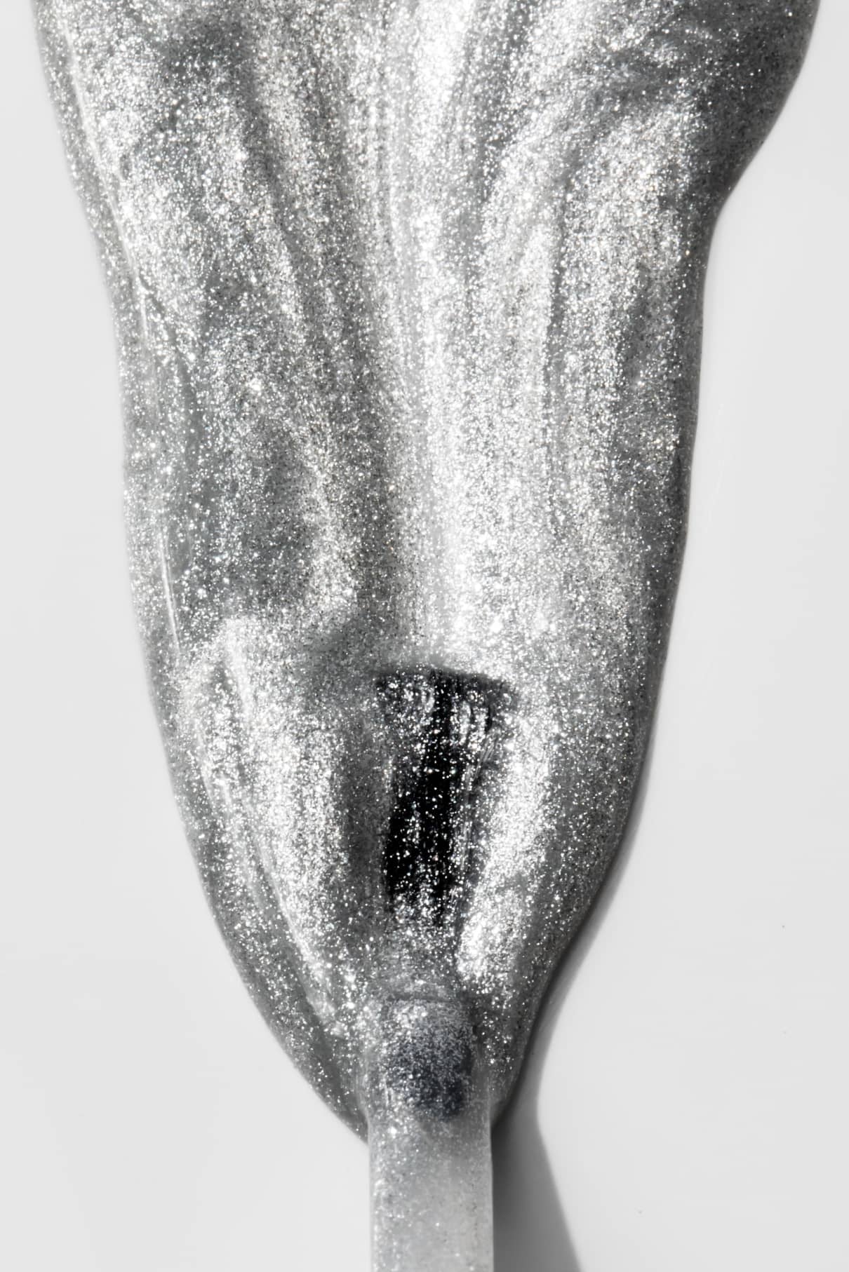 Nahaufnahme eines Pinselstrichs von gitti no. 201 Metallic-Nagellack in kühlem Silber mit schimmernder, glitzernder Textur auf weißem Hintergrund.