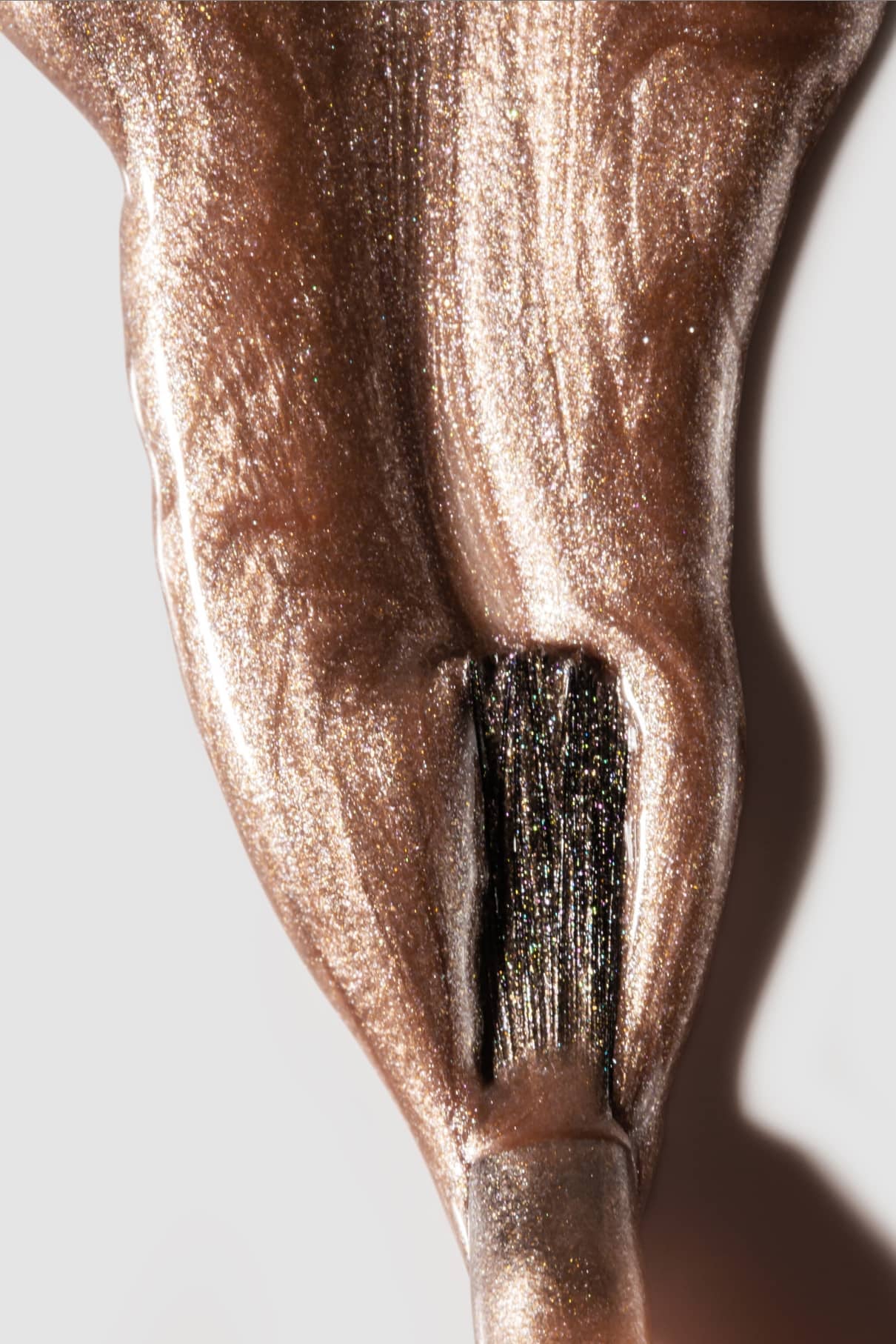 Nahaufnahme eines Pinsels, mit dem gitti no. 209, ein metallisch schimmernder Bronzenagellack, auf eine weiße Fläche.