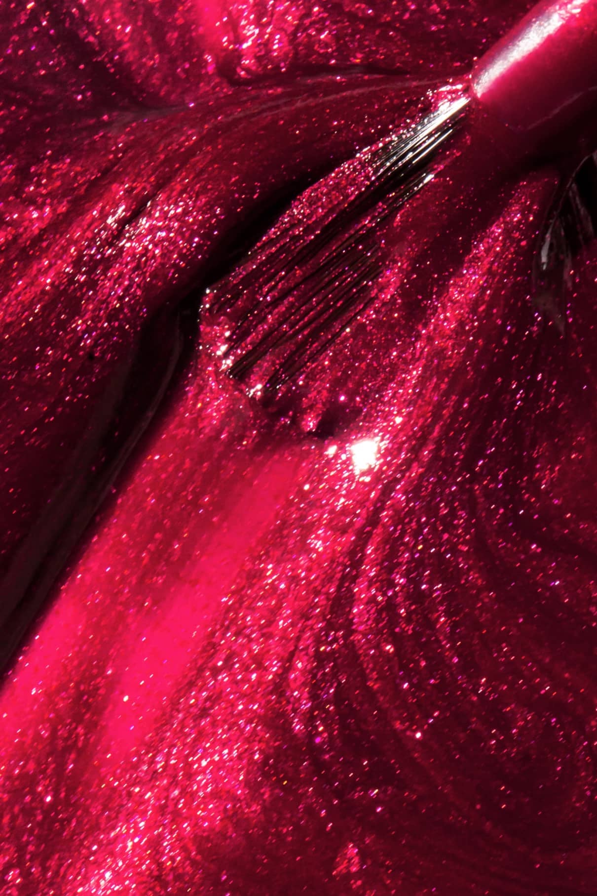 Nahaufnahme eines Pinsels, der gitti no. 212, ein schimmernder, metallischer fuchsiafarbener Nagellack mit sichtbarer Textur und Glitzern in edlem Metallic-Schimmer und beerigem Rot.