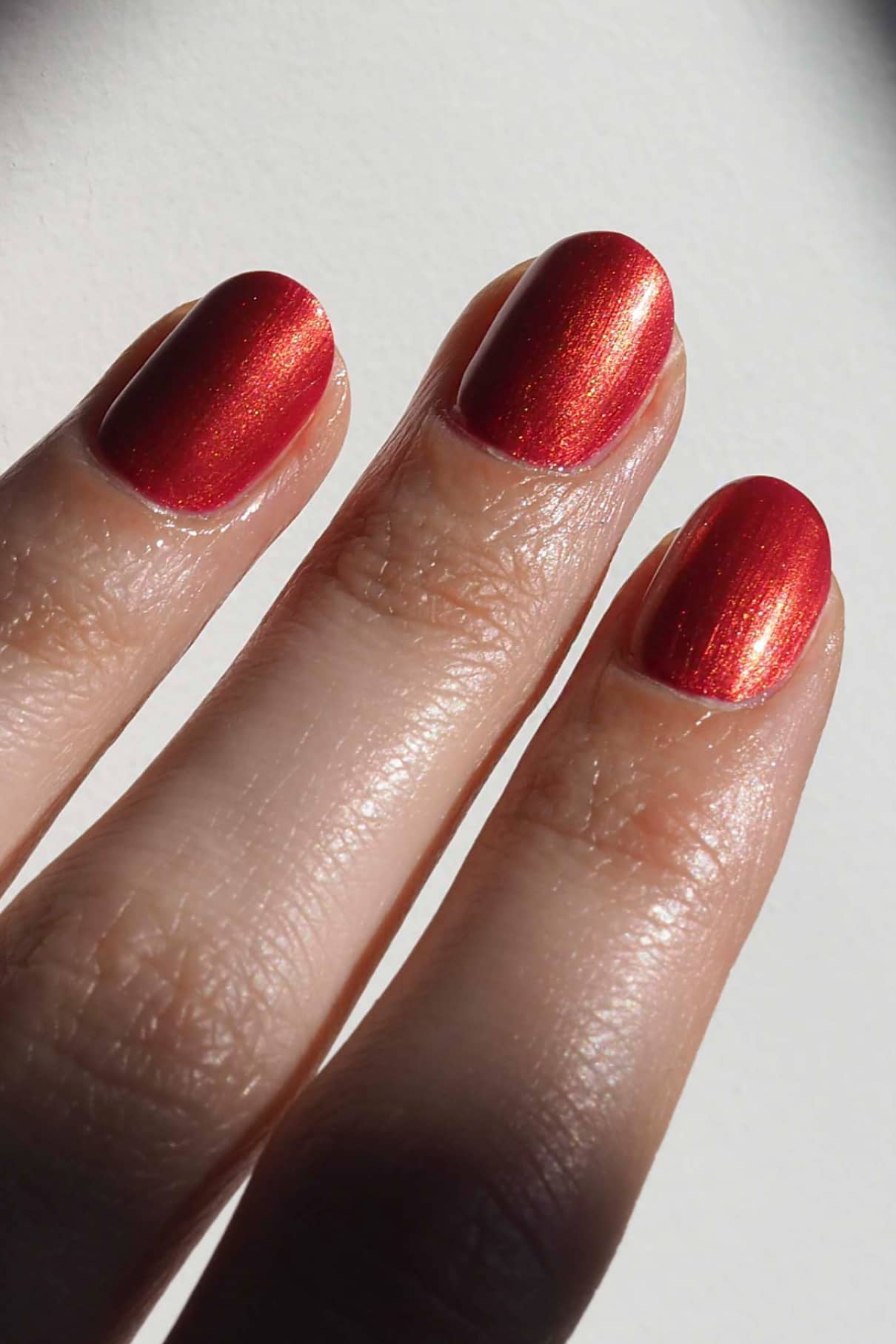 Eine Nahaufnahme von Fingern mit gitti no. 301, einem leuchtenden Rotton Nagellack.