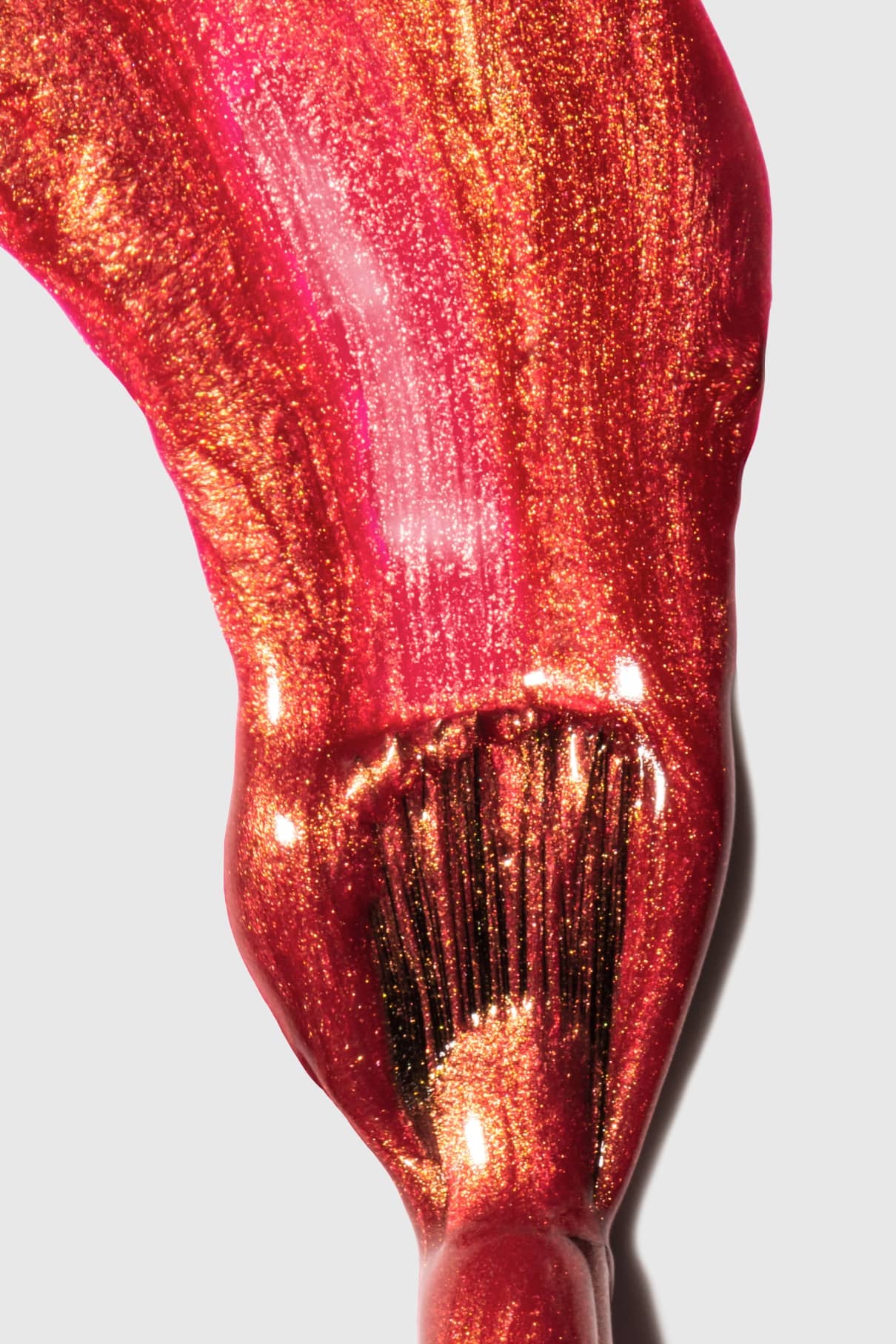 Nahaufnahme eines Pinselstrichs, mit dem der glänzende, leuchtende Rotton gitti no. 301 Nagellack auf eine weiße Fläche auf.